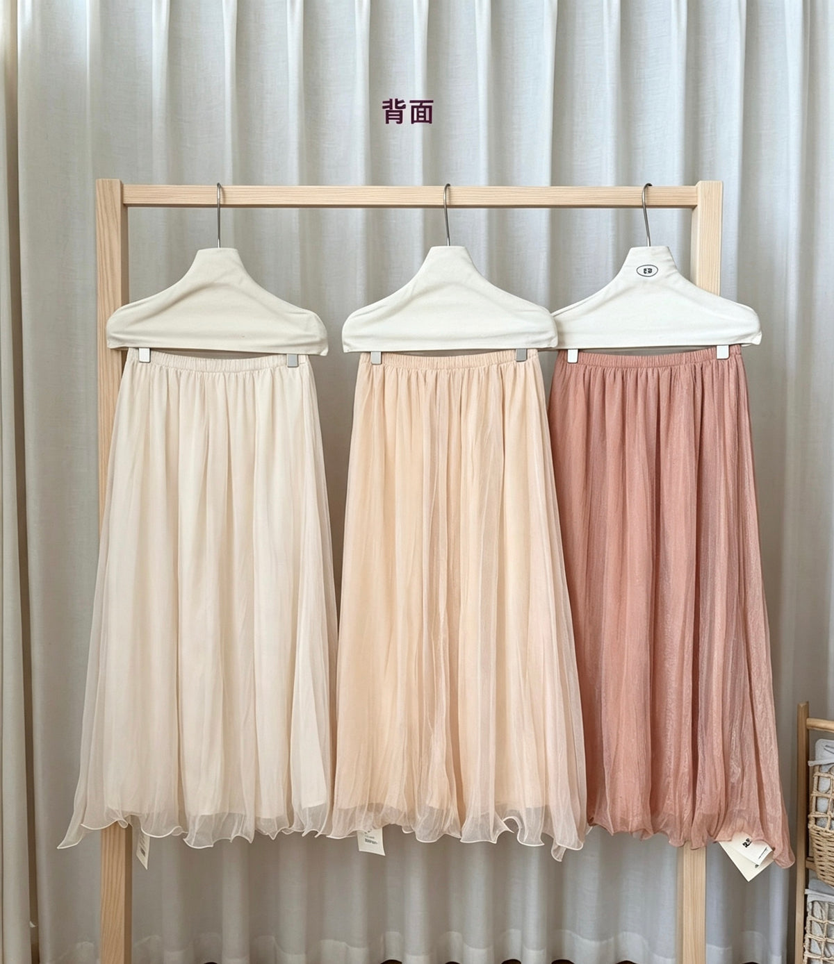 Back view of the three pearlescent mesh skirts on a wooden rack