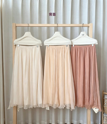 Back view of the three pearlescent mesh skirts on a wooden rack