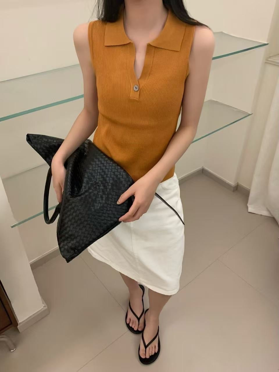 Model wearing sunset orange ribbed sleeveless polo top with white skirt