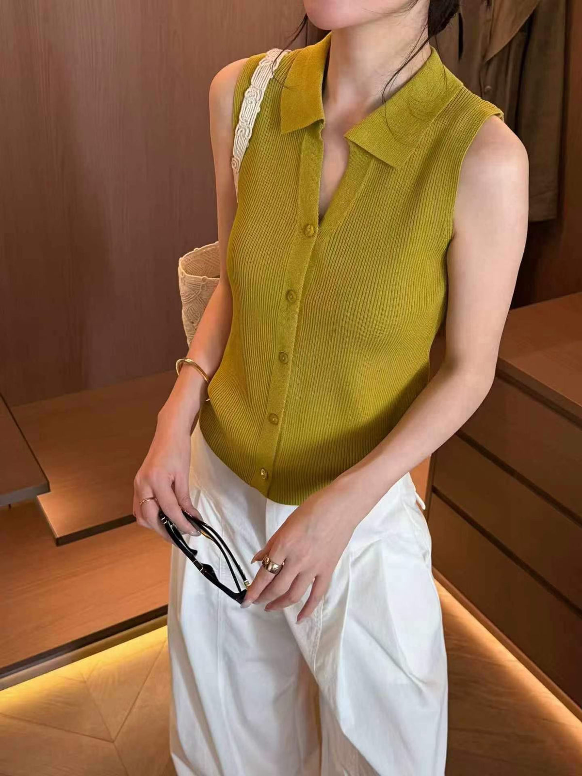 Model wearing mustard yellow sleeveless ribbed knit polo top