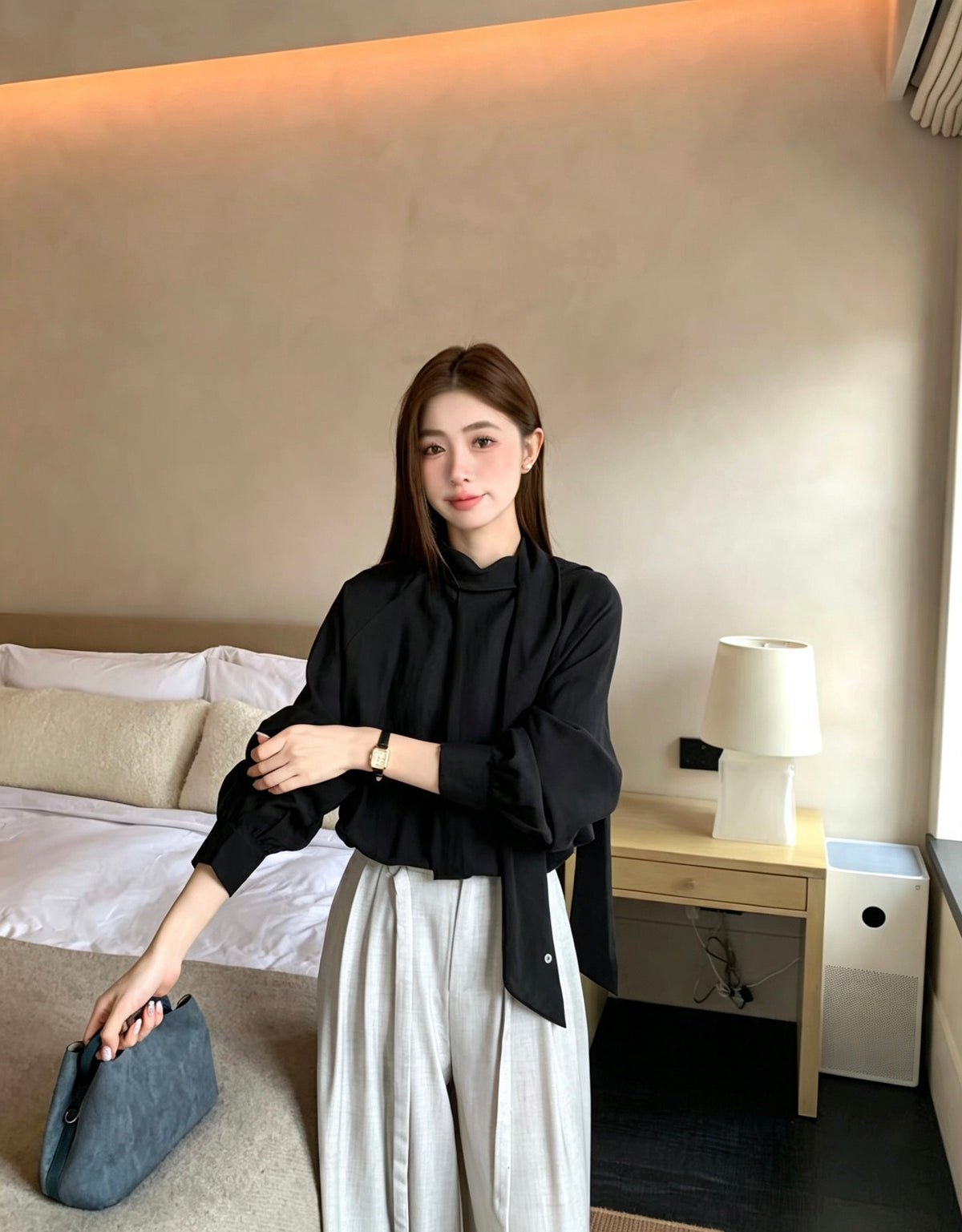 Model wearing a black two-way tie blouse adjusting her sleeve.