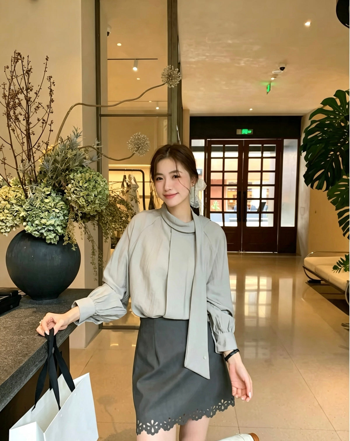 Model wearing a grey two-way tie blouse and dark grey skirt.