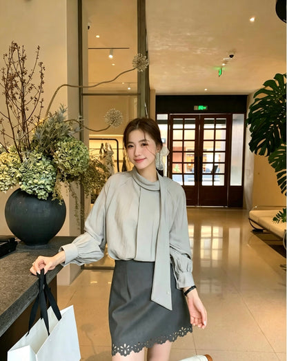 Model wearing a grey two-way tie blouse and dark grey skirt.