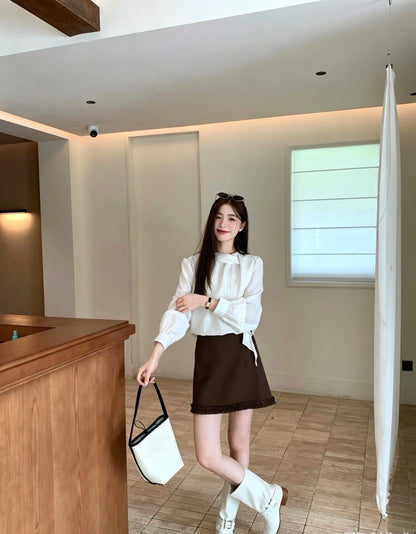 Model posing in a white French design shoulder button tie blouse