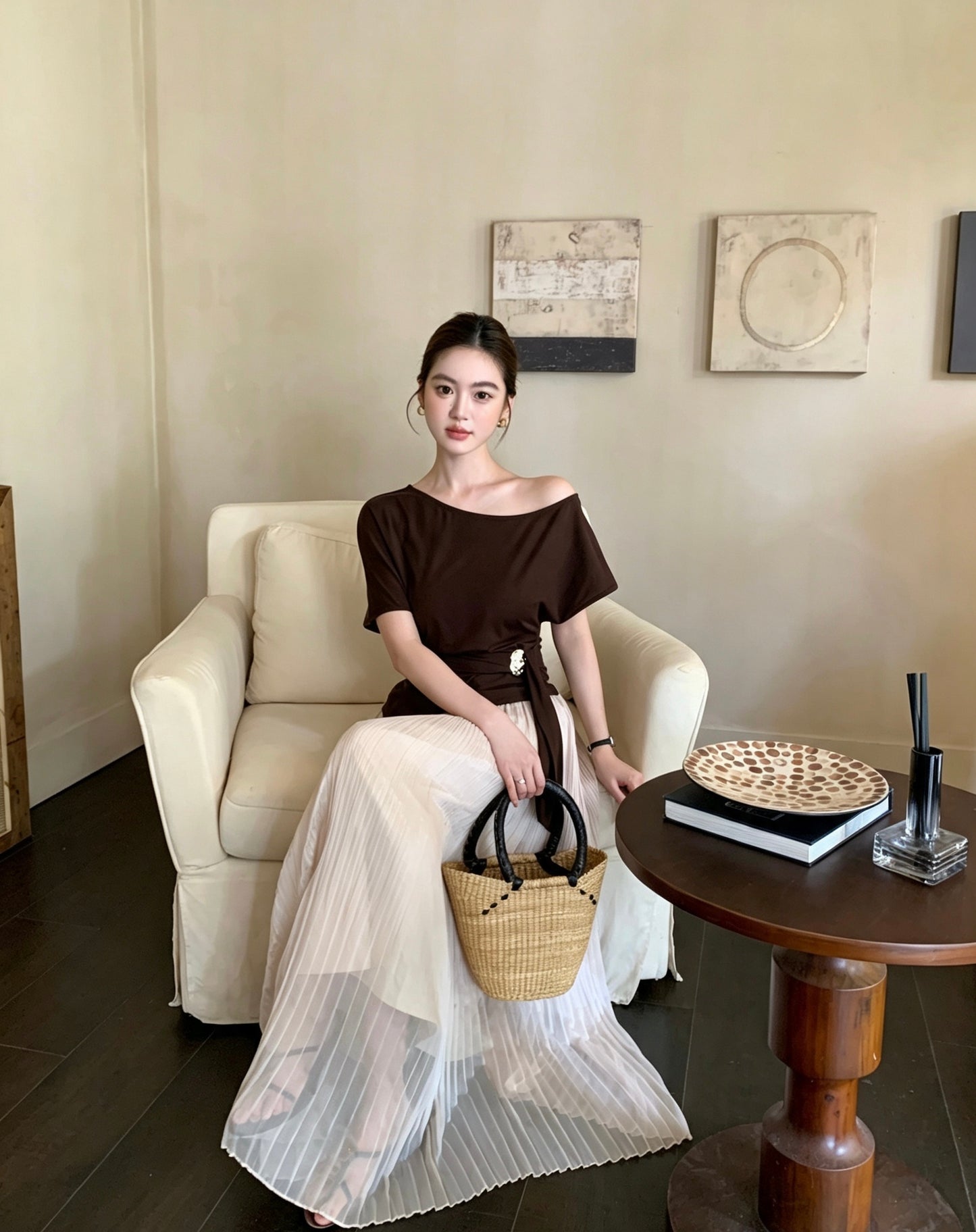 Model sitting in an apricot pleated maxi skirt and brown top