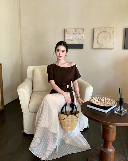 Model sitting in an apricot pleated maxi skirt and brown top