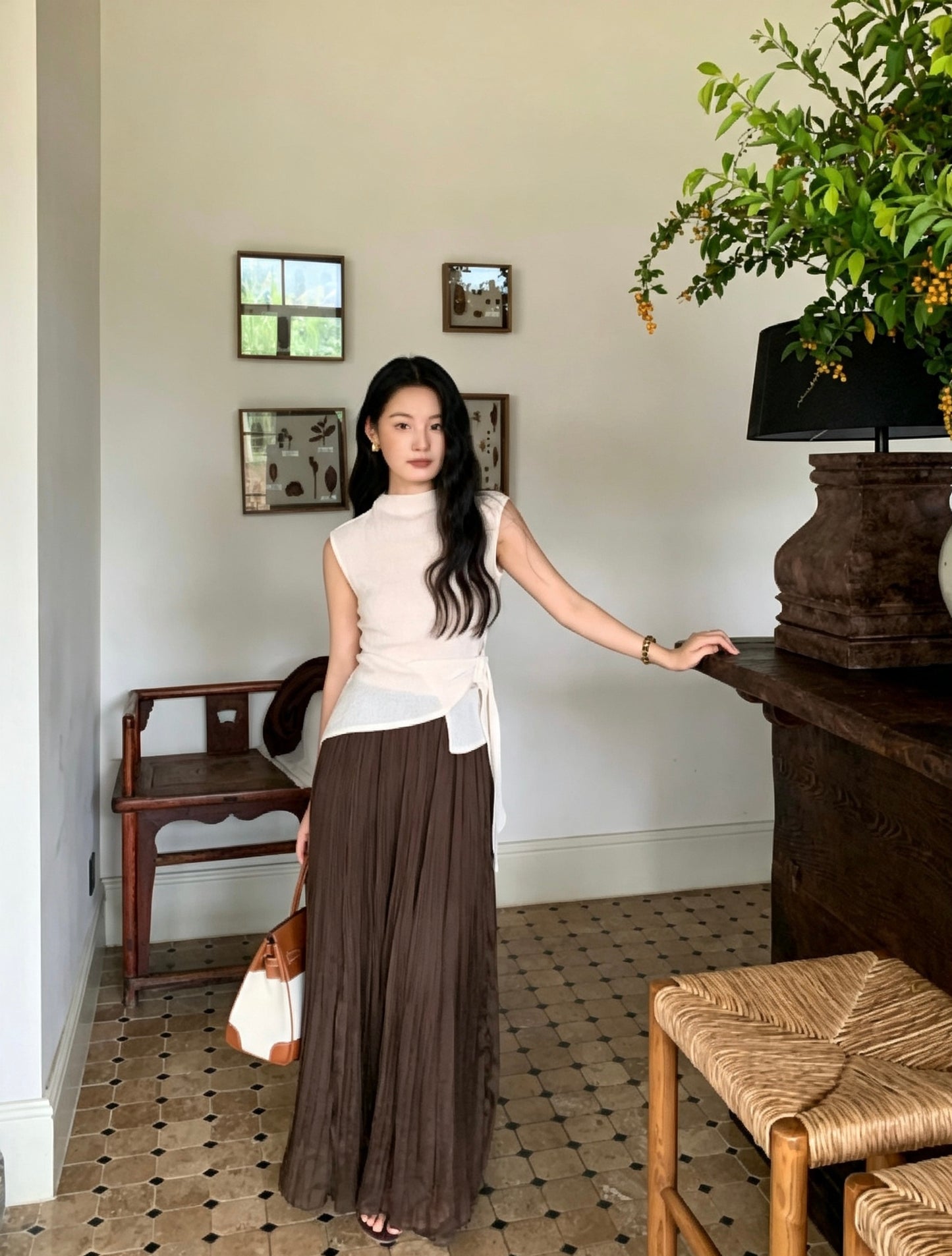 Model in white sleeveless top and brown skirt