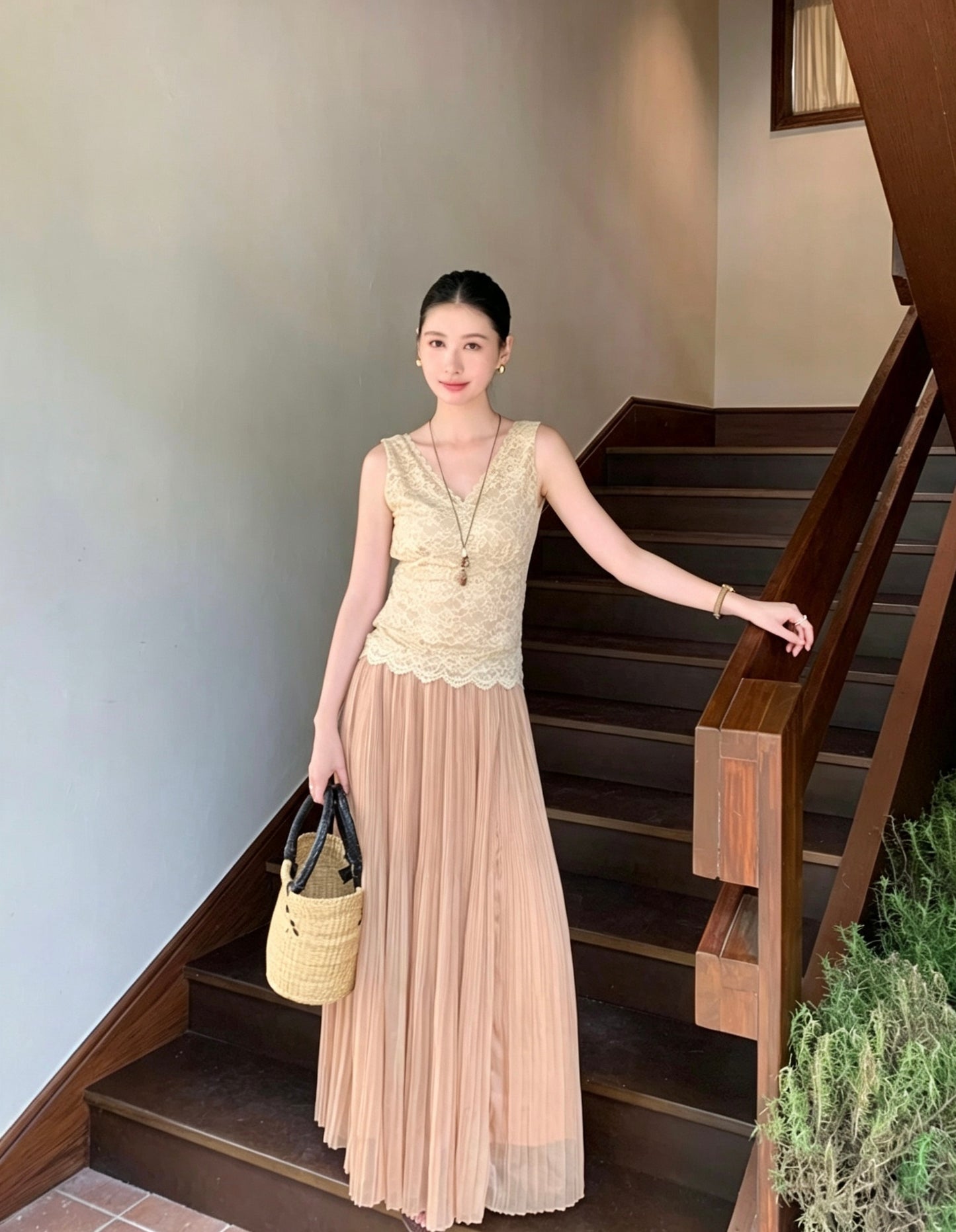 Model wearing an apricot pleated maxi skirt standing on stairs