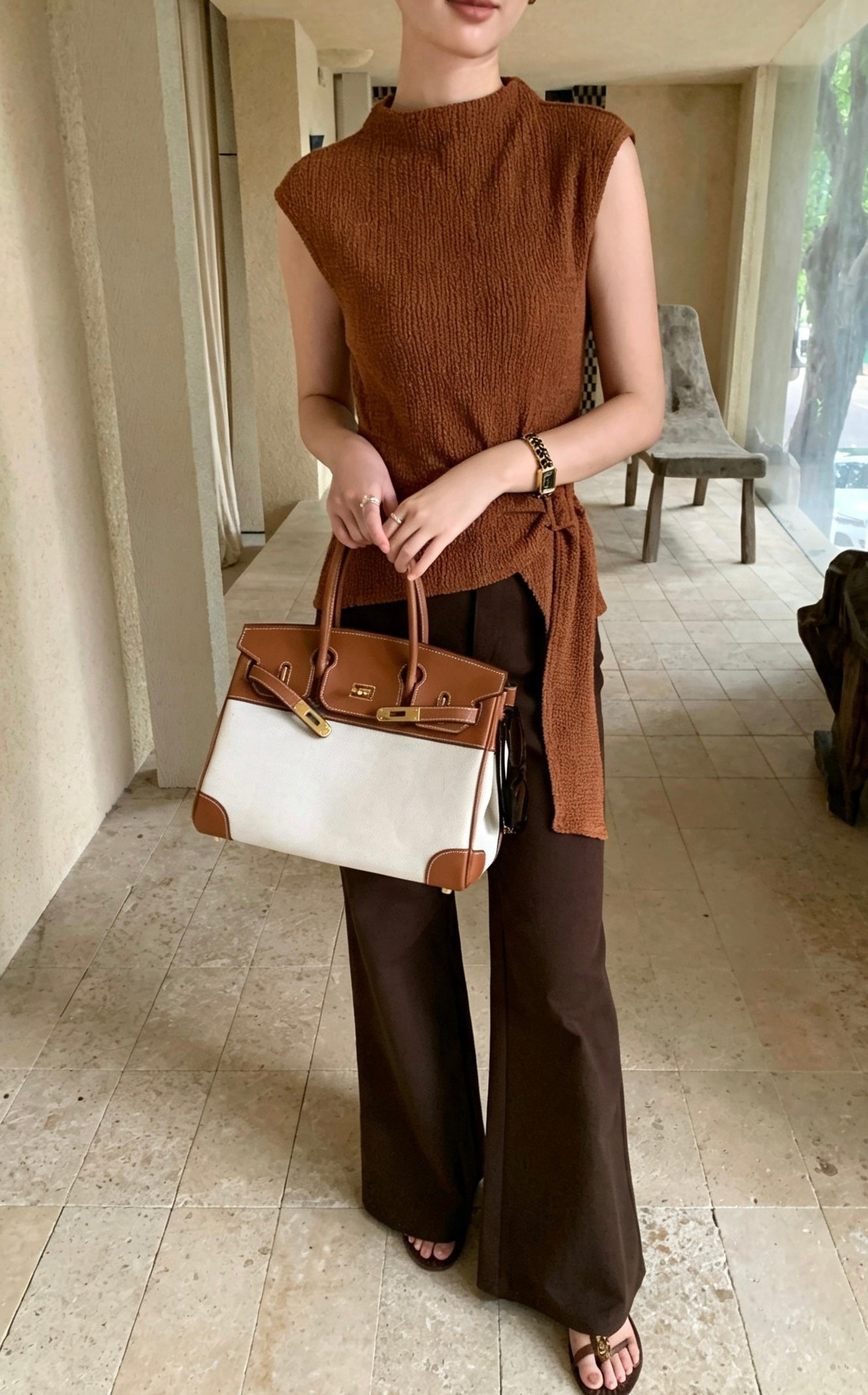 Model in coffee sleeveless top and brown pants