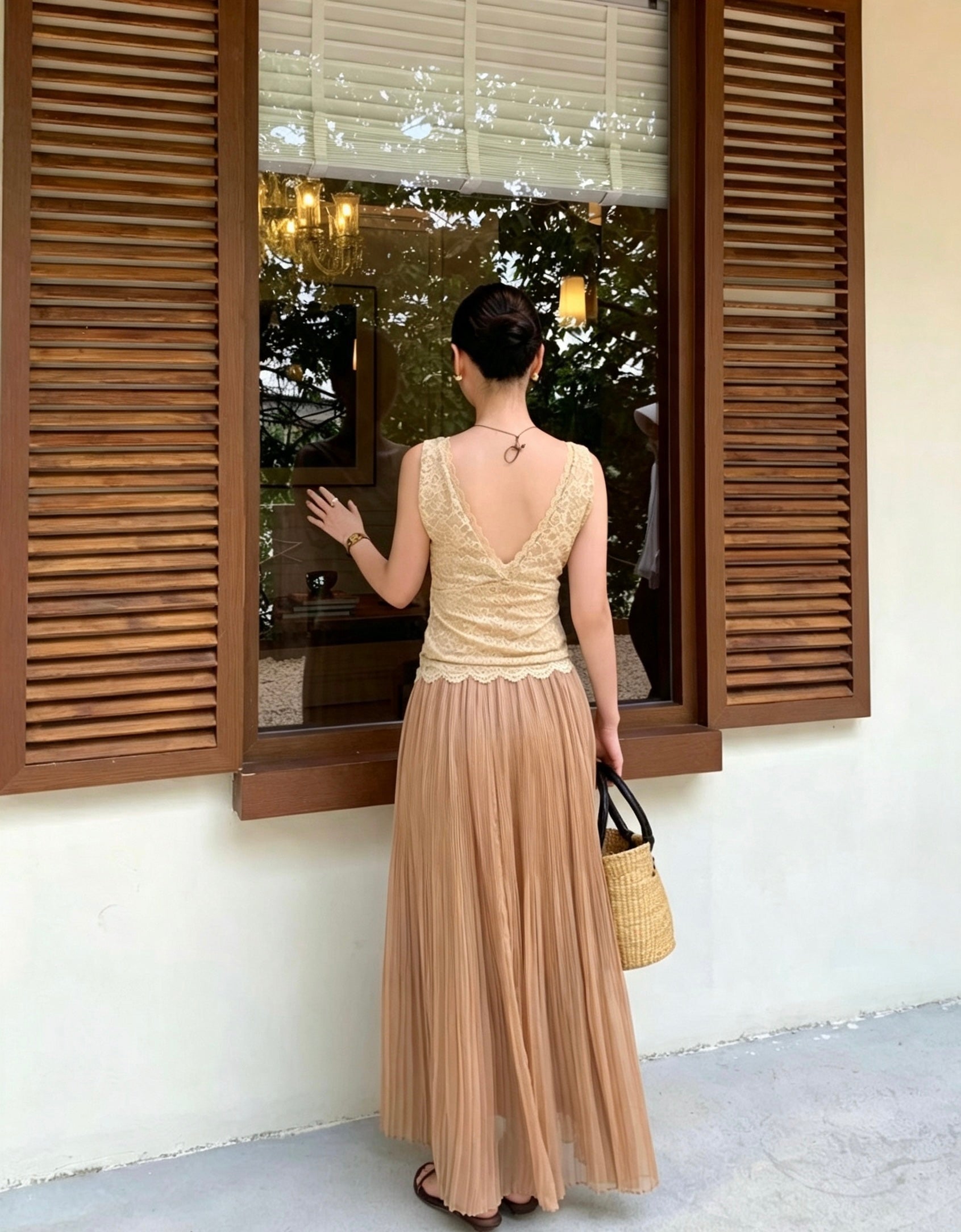 Back view of a model in an apricot pleated maxi skirt