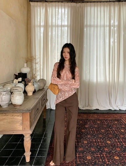 Model with arms crossed wearing brown sheer asymmetrical shirt