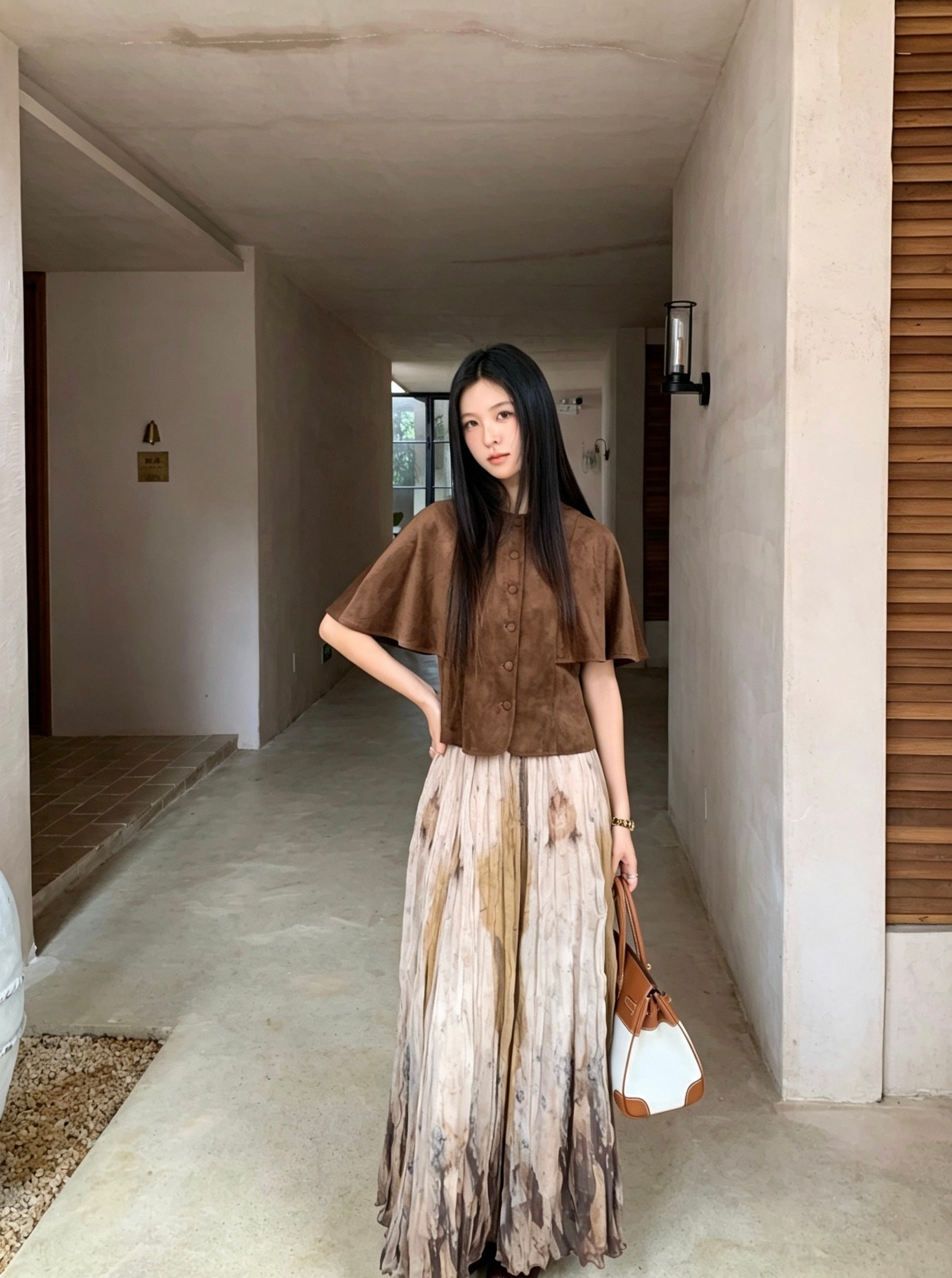 Model wearing a khaki tie-dye print pleated flowy skirt and brown top