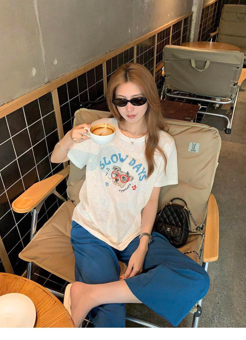 Woman sitting down wearing a white cute dog graffiti t-shirt