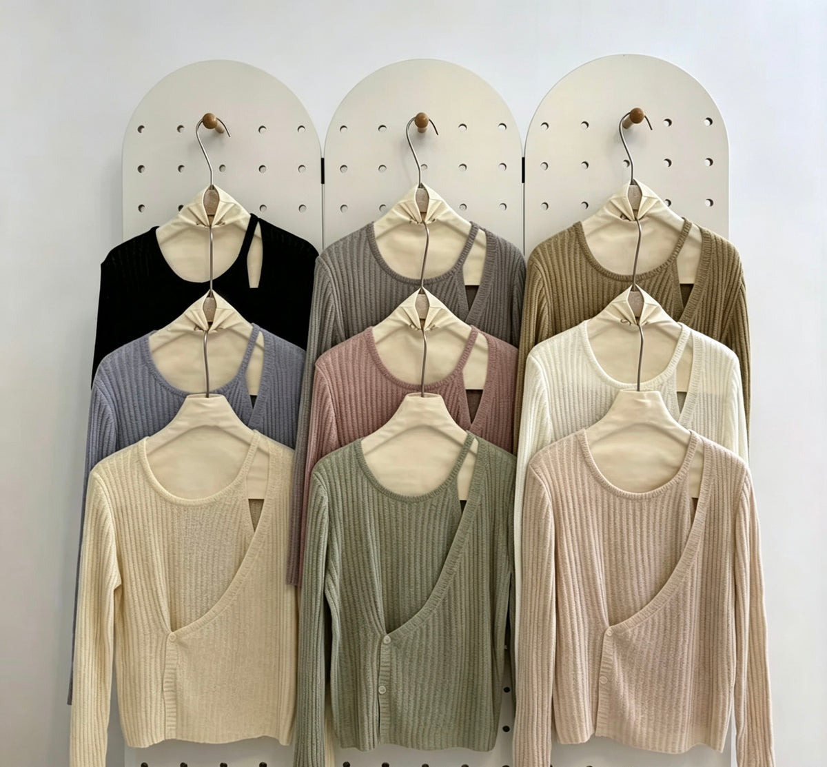 Various colors of ribbed knit tops with button cutout on a pegboard