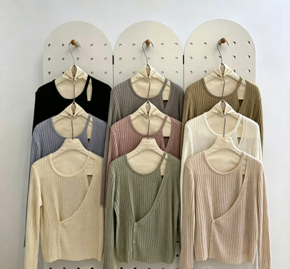 Various colors of ribbed knit tops with button cutout on a pegboard