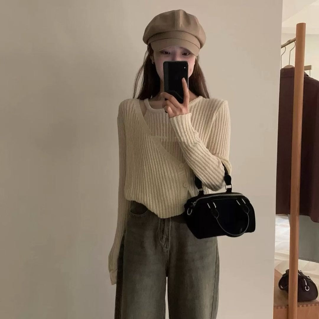 Model taking a mirror selfie in a beige ribbed knit top with a black handbag