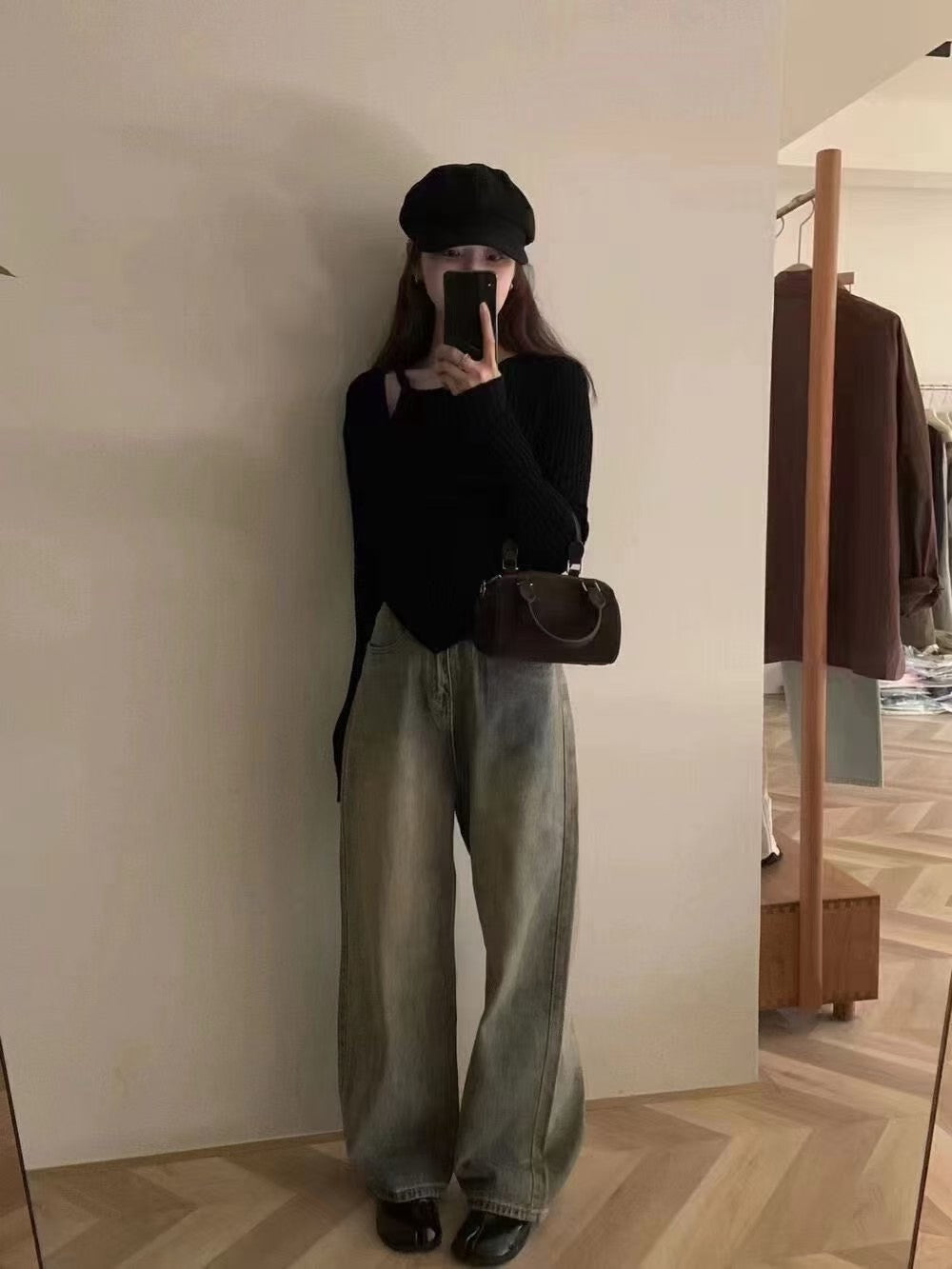 Model wearing a black ribbed knit top with asymmetrical button cutout