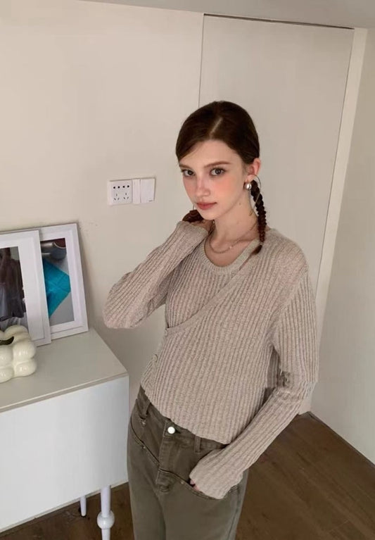 Model wearing a beige ribbed knit top with asymmetrical button cutout