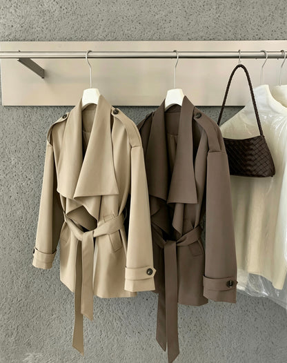 Beige and coffee brown trench coats hanging side by side on a rack