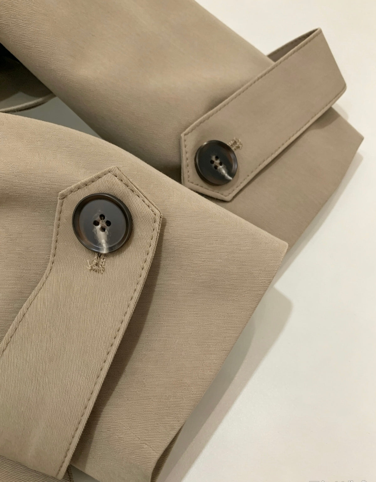Close-up of beige trench coat sleeve cuffs with button details