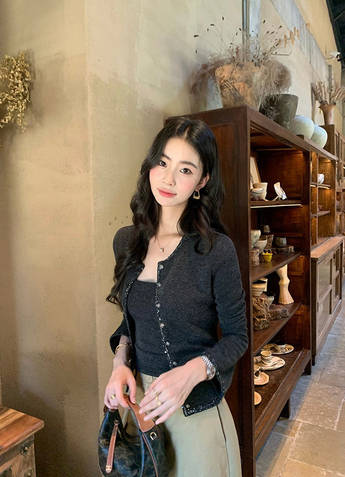 Elegant woman wearing a dark grey knit set in a rustic indoor setting