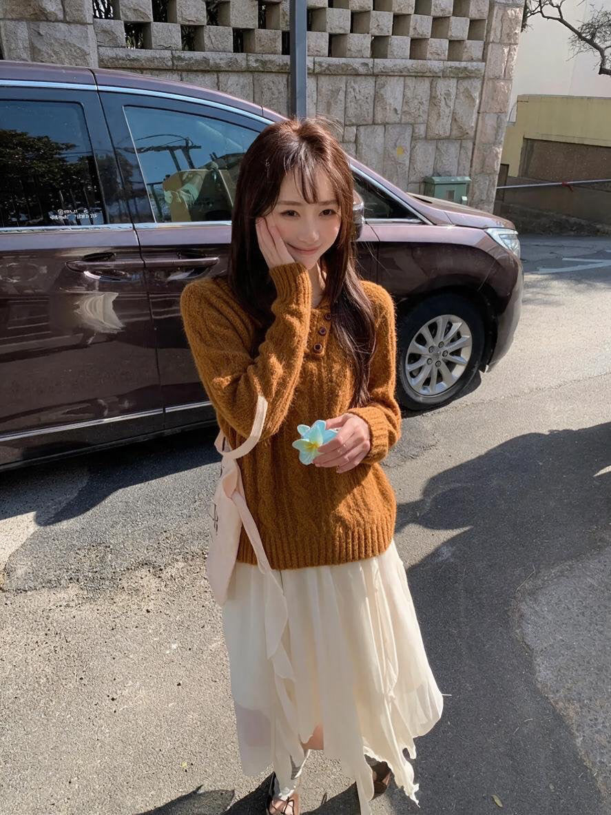 Woman wearing orange asymmetrical button cable knit sweater