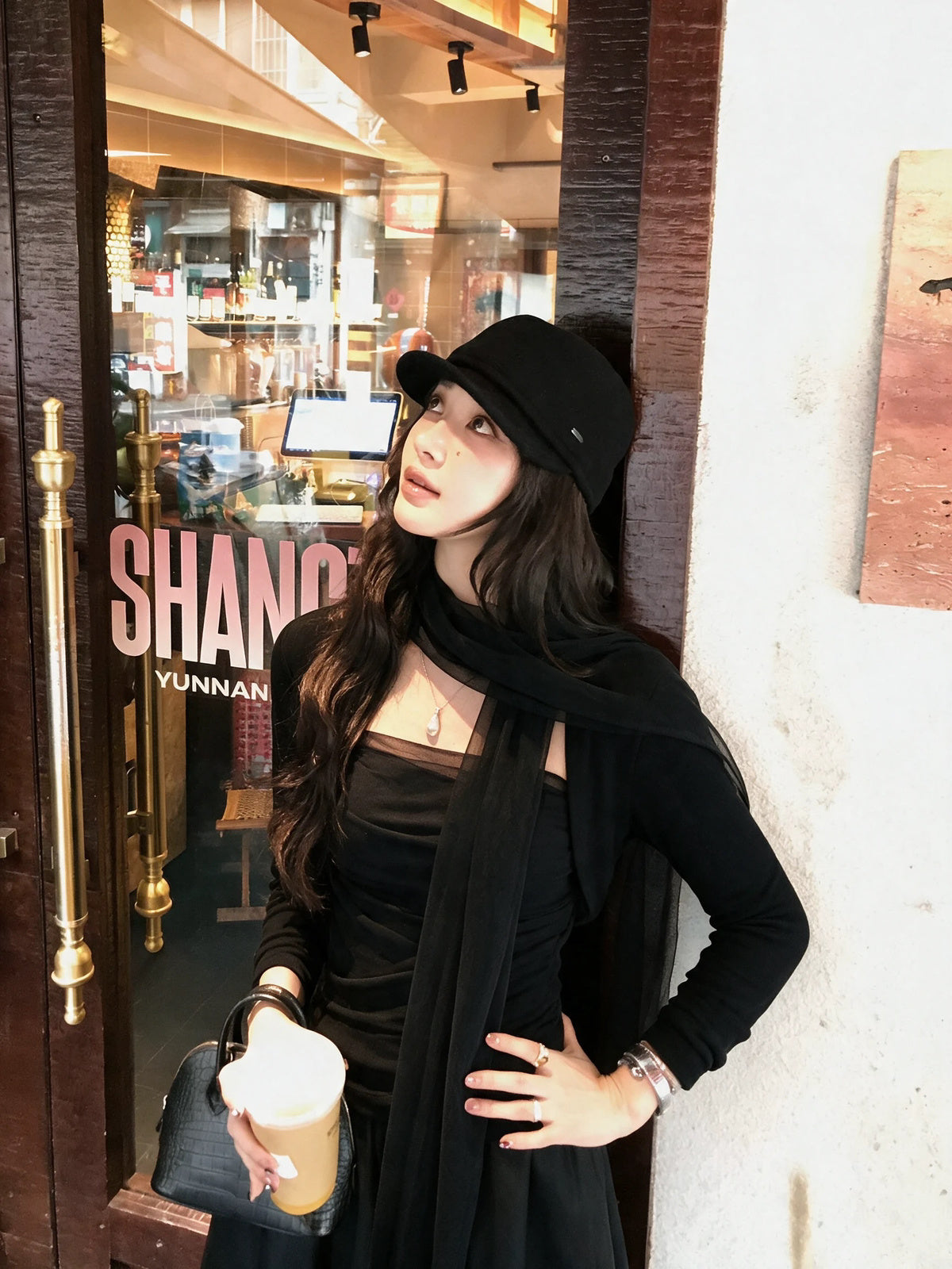 Model wearing black outfit with scarf