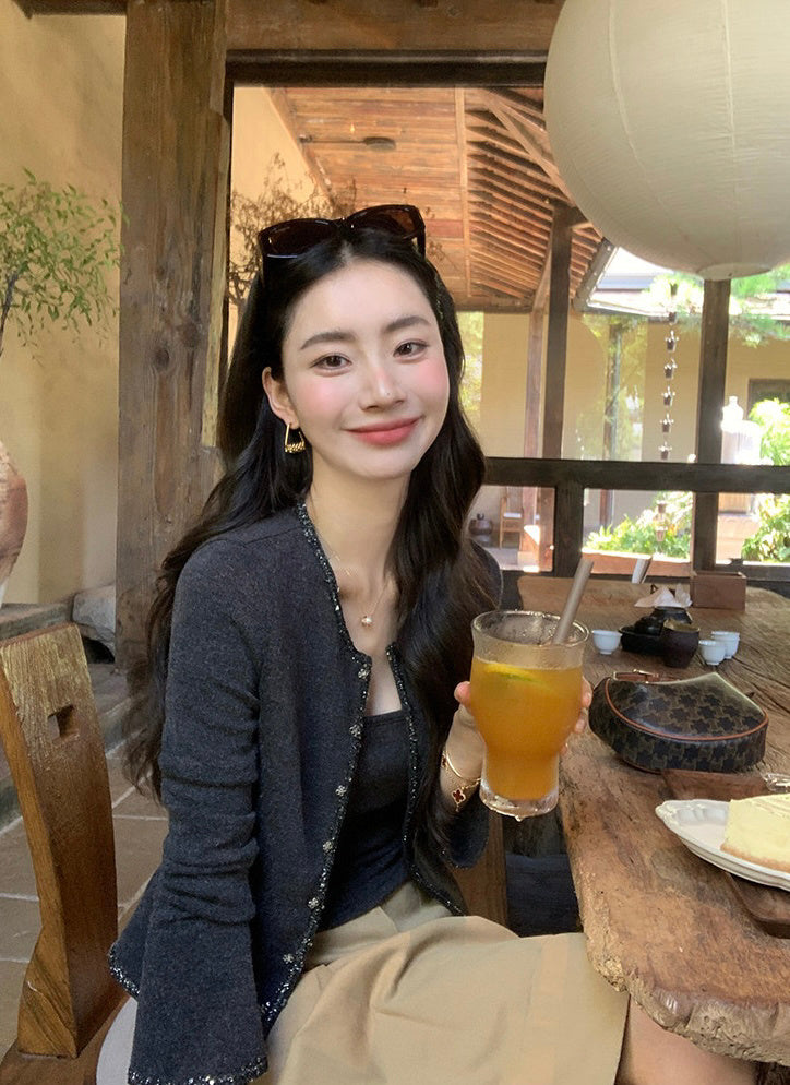 Woman sitting at a table wearing a dark grey cardigan set
