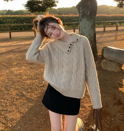 Woman wearing khaki asymmetrical button cable knit sweater