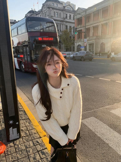 Woman wearing beige asymmetrical button cable knit sweater