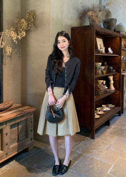 Model in a dark grey two-piece knit set and beige midi skirt