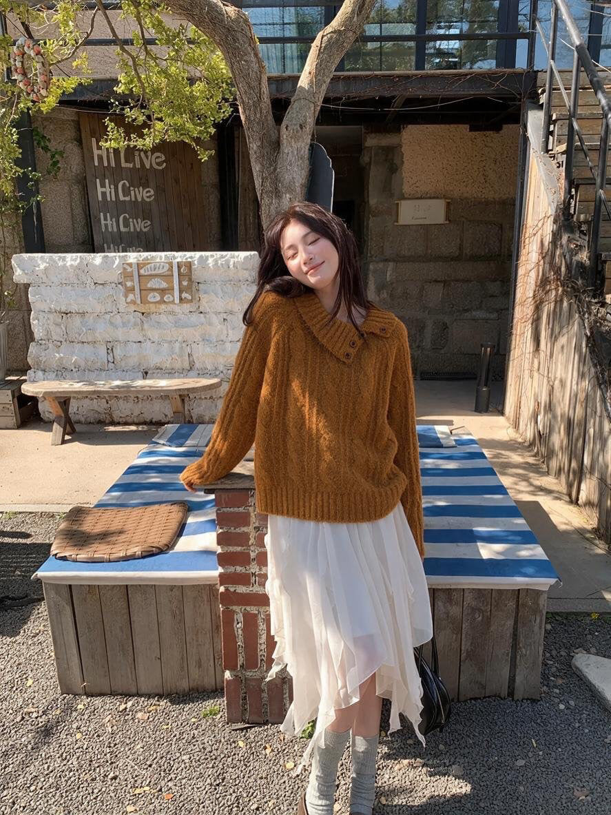 Woman wearing orange asymmetrical button cable knit sweater