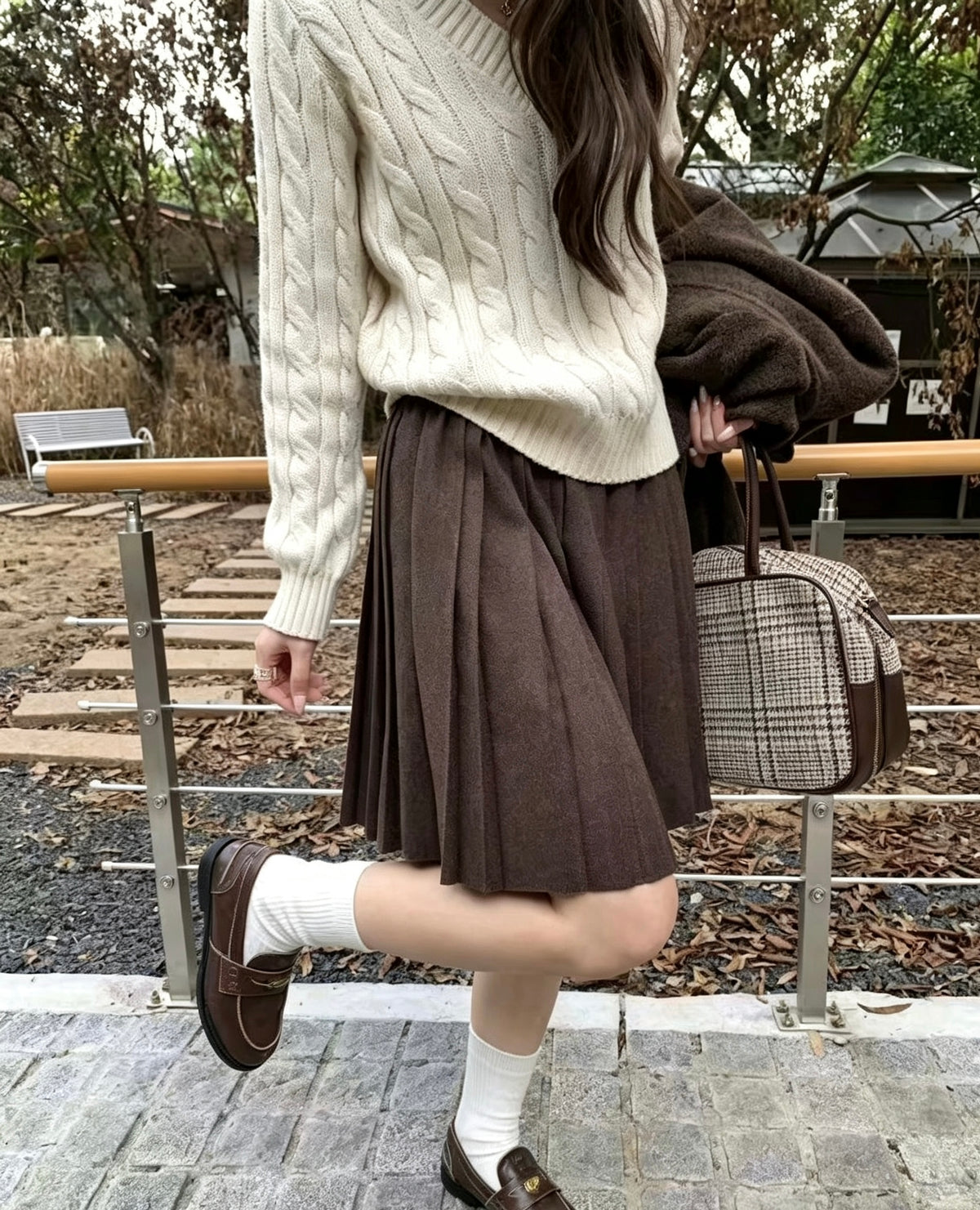 Model in dark brown knit pleated skirt and white cable knit sweater
