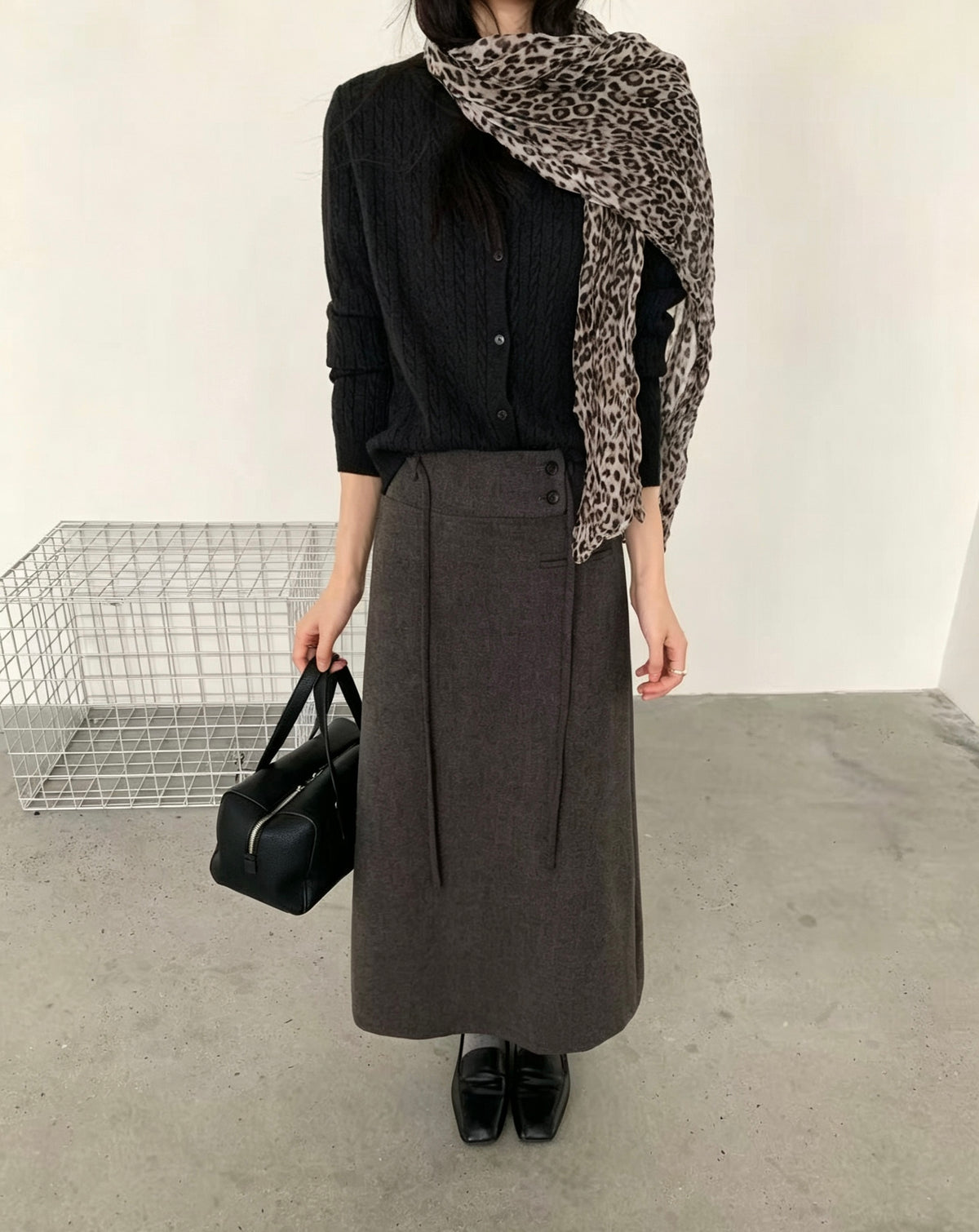 Model wearing a dark grey Korean retro draped high-waisted A-line skirt with a black cardigan and leopard print scarf
