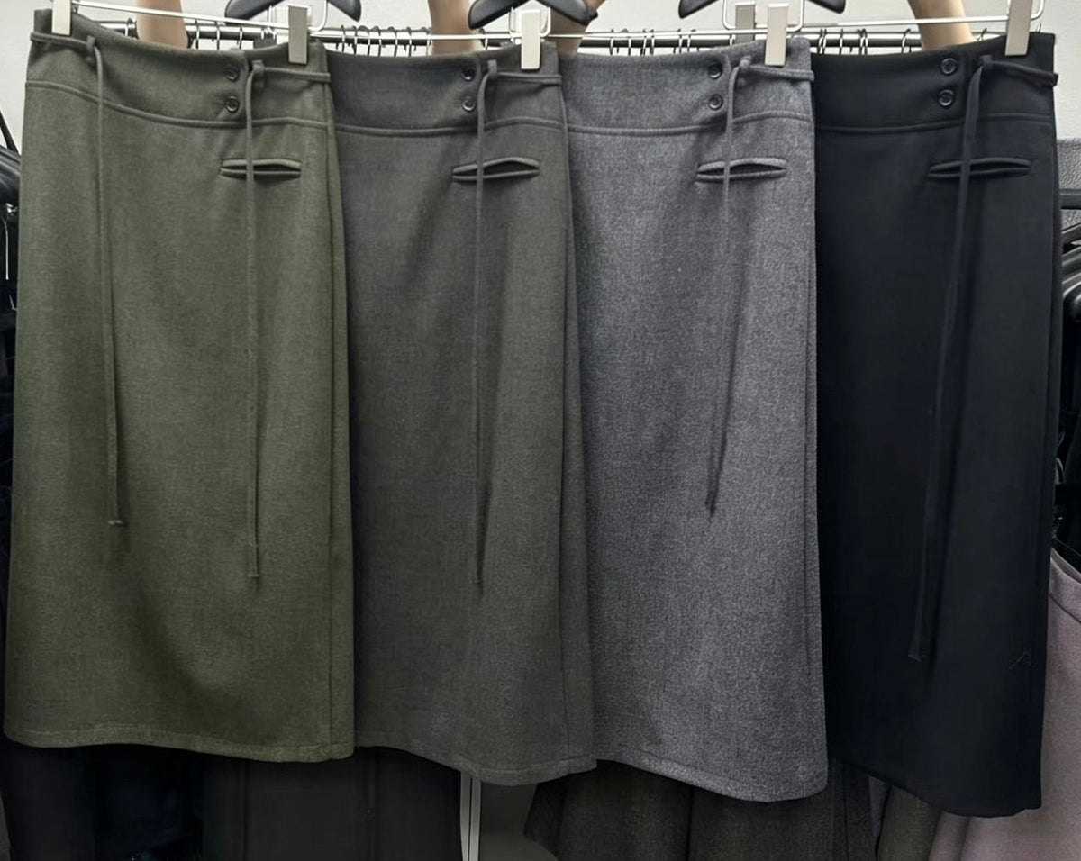 Four Korean retro draped high-waisted A-line skirts in olive green, dark grey, light grey, and black hanging on a rack