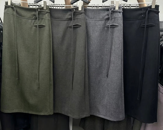 Four Korean retro draped high-waisted A-line skirts in olive green, dark grey, light grey, and black hanging on a rack