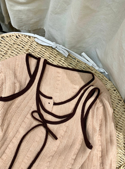 Flat lay of orange-pink ribbed knit camisole with brown trim and bow