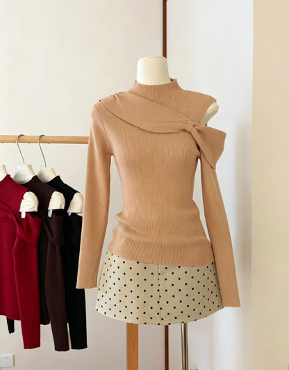 Front view of orange-pink bow twist cold shoulder knit top on a mannequin